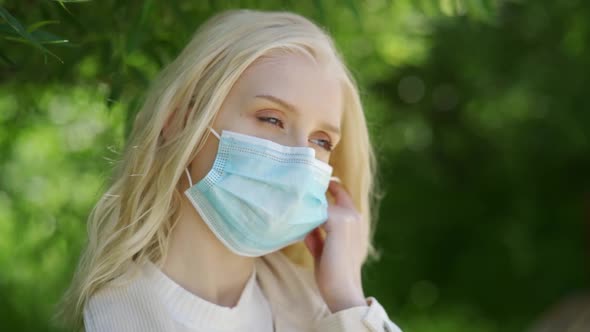 Young Blonde Woman with Blue Eyes Takes Off the Medical Mask and Enjoys the Fresh Air