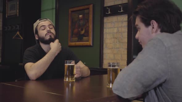 Two Men Drinking Beer Sitting at a Table in a Pub alt