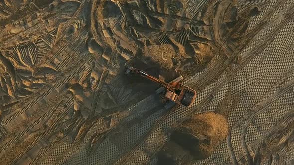 Excavator Evens Sand Surface at Construction Site During Sunset