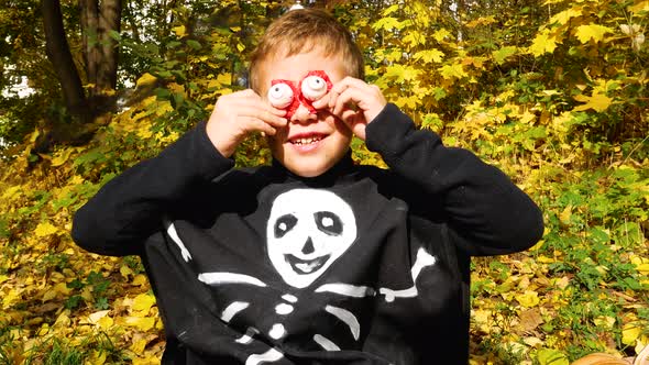A Boy in a Skeleton Costume During Halloween Puts Terrible Eyes to His Face and Frightens Everyone