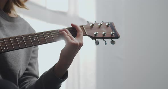 A Teenager Plays Guitar in a White Living Room with Beautiful Sunlight alt