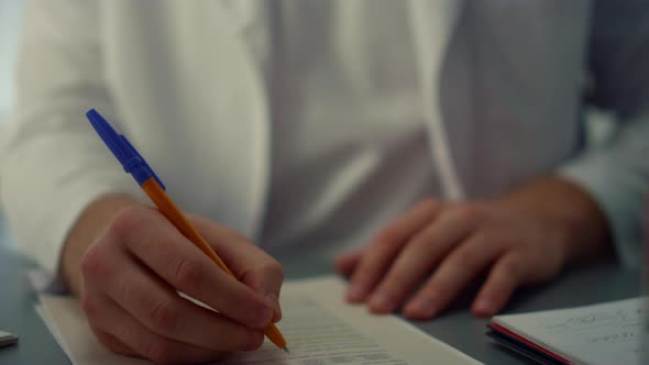 Man Surgeon Writing Notes in Medical Journal Sitting Hospital Office Close Up alt