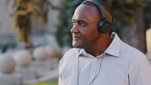 Carefree Emotional Senior African American Man Sitting Outdoor Relishing Weekend in Park Drinking alt