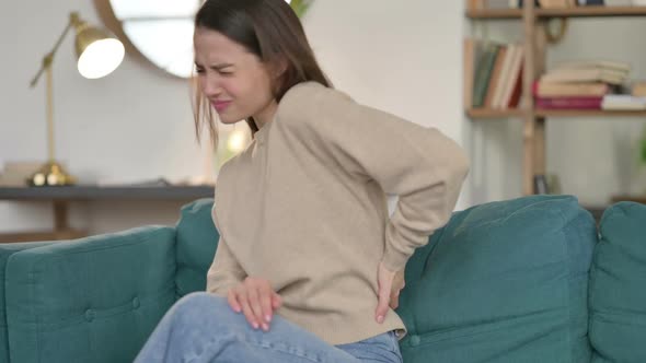 Young Woman with Back Pain Sitting on Sofa alt