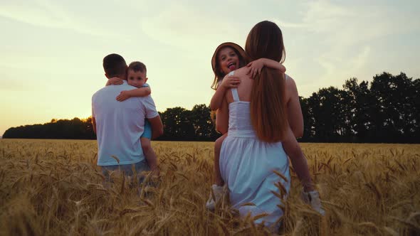 Slow Motion Parents Walking in Field with Kids in Arms alt