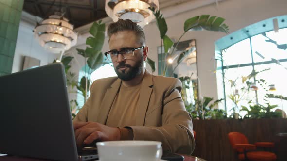 Caucasian Businessman Working on Laptop in Cafe alt
