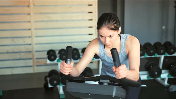 Pretty Woman in the Gym Exercising Her Legs Doing Cardio Training on Bicycle alt