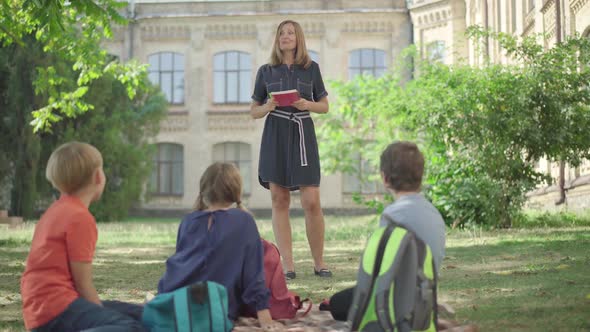 Outdoor Lesson for Middle School Students. Wide Shot of Confident Positive Caucasian Woman Talking alt