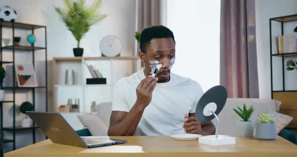 African American Sitting in front of Small Mirror and Applying Face mask alt