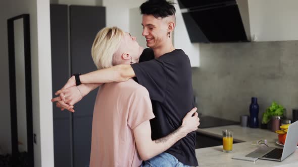 Gay Male Couple Hugging and Kissing in Kitchen a Man Sitting on a Counter alt