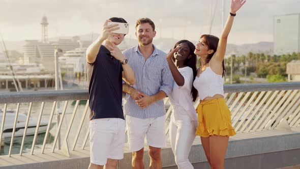 Happy Multiethnic Friends Making Selfie on Smartphone While Standing in Seaport Outdoors alt