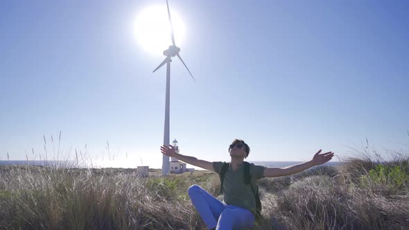 Young man looking at the sky with both hands out to the side. alt