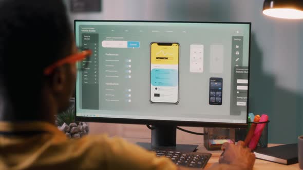 Black Male Creating Cellphone App on Computer alt