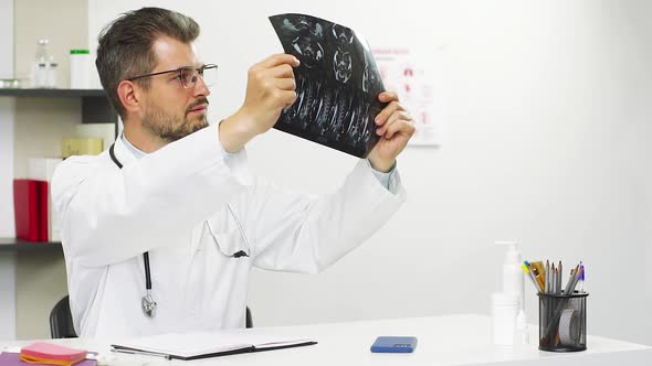 Doctor Learning X-ray of Patient and Noting the Results Down alt