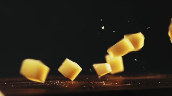 Pieces of Hard Cheese with Crumbles Fall Down Onto Table alt