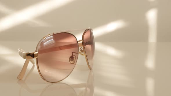 Modern style sunglasses on white reflective surface close-up 4K 2160p UltraHD tilt footage - Dark sh alt