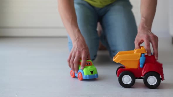 An adult man is playing with a toy car on the floor.