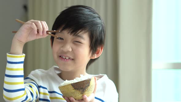 Cute Asian Boy Eating Rice With Chopsticks alt