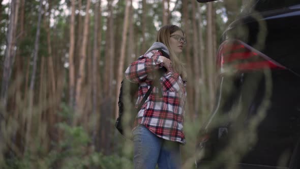 Side View Confident Woman Putting Wicker Basket and Backpack in Car Closing Trunk in Slow Motion alt
