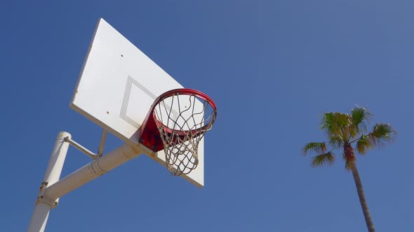 A man does a slam dunk while playing one-on-one basketball hoops on a beach court alt