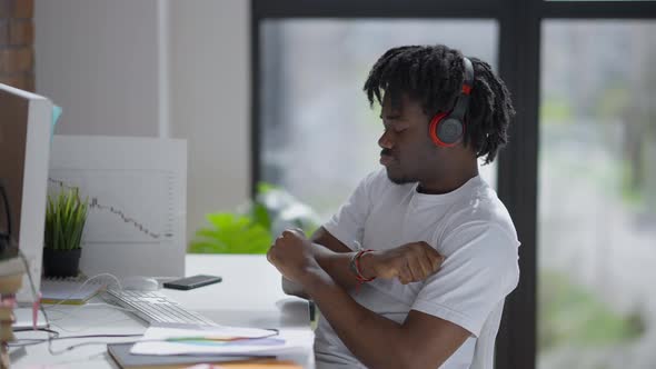 Joyful African American Man Enjoying Music in Headphones Sitting at Computer Table in Home Office alt