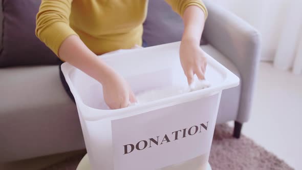 Woman selecting clothes for donation. Clothing donations concept. alt