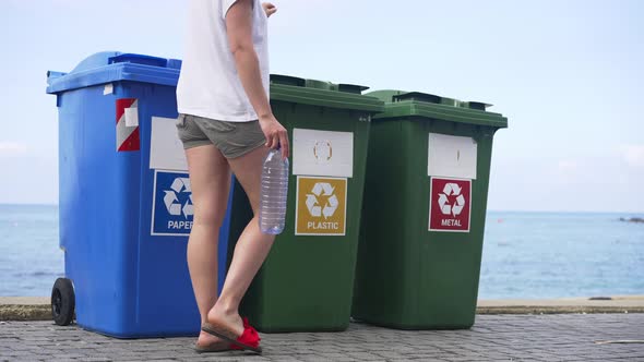 Containers for Separate Waste Collection on Sea Beach with Young Slim Caucasian Woman Passing alt