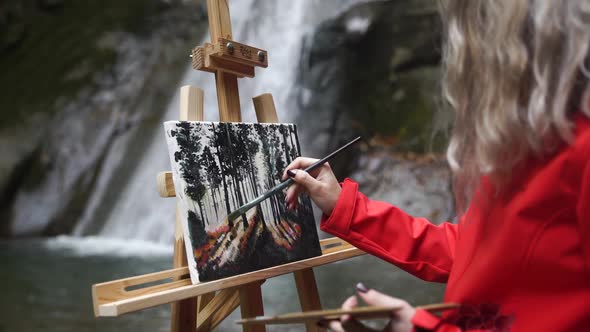Painter Painting Outside Close to the Waterfall 
