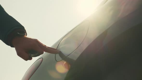 Man Opens Cap Connecting Plug to Electric Car at Sunlight alt
