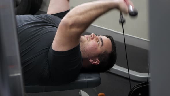 Young male using machine weights to train. He performs an isolated triceps curl. CLOSE UP. alt