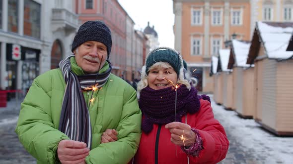 Senior Couple with Burning Sparklers Bengal Lights Celebrating Anniversary Making a Kiss on Street alt