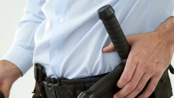 Mid section of security guard holding baton and walkie talkie alt