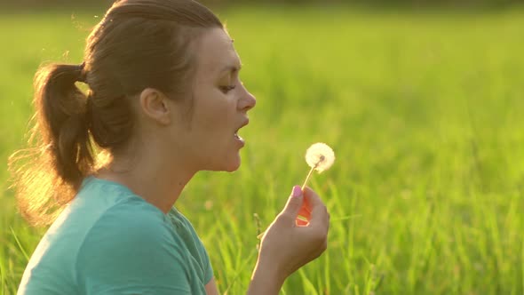 Portrait of a Beautiful Young Woman Blowing on the Ripened Dandelion alt