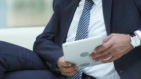 Businessman Sitting on Couch and Texting on Tablet alt