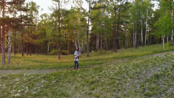 Young Couple Walking on a Mountain Path. Woman Piggyback Ride Boyfriend alt