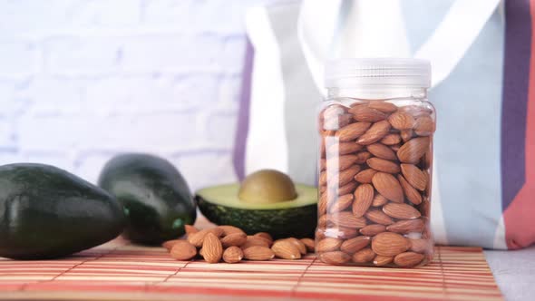 Close Up of Slice of Avocado and Almond Nut on Chopping Board alt