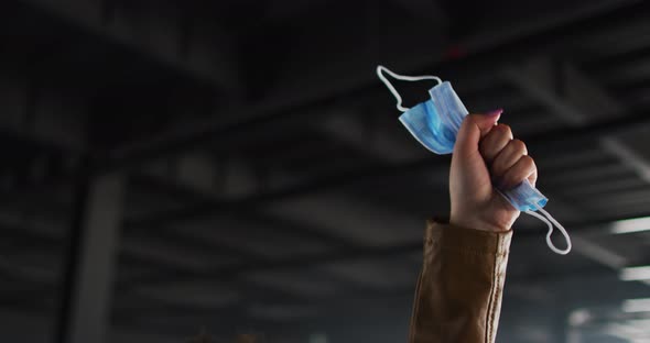 Part of african american woman hand protesting while holding face mask in empty parking garage alt