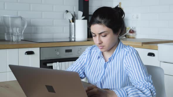 Young female using laptop writing notes stand at home office desk, business woman professional  alt