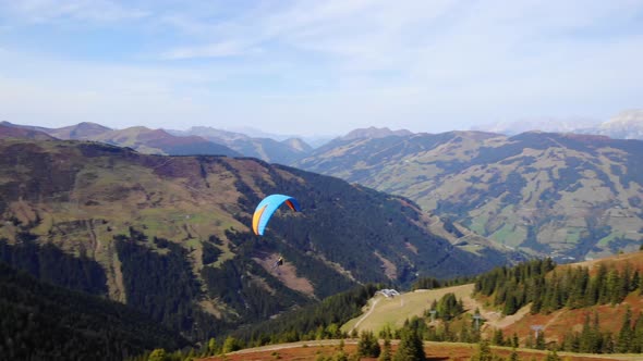 Paragliding - Tourists Fly In The Sky With A Colorful Parachute Over Mount Schmitten In Austria. aer alt