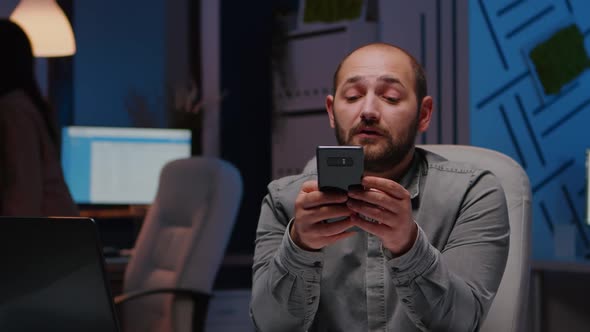 Entrepreneur Man Smiling at Phone While Writing Financial Strategy Planner alt
