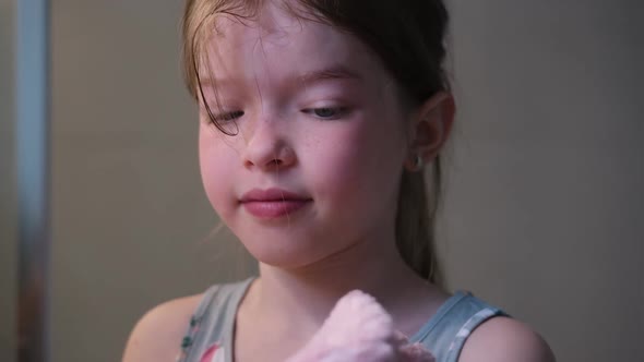 Little Girl Wipes Her Face with a Towel in the Bathroom After Washing Her Face