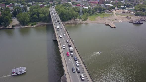 Drone Is Flying Over River with Bridge with Moving Cars in Summer Day