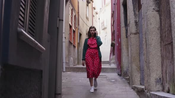 Woman Tourist Is Walking in Old Narrow Street and Talking on Mobile Phone alt