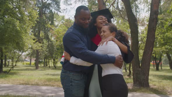 Joyful Proud Multiethnic Parents Embracing Cheerful Female Graduate with Diploma alt