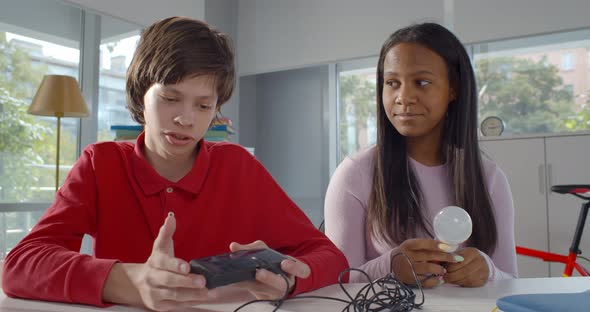 African Girl and Caucasian Boy Present Electric Invention at Online Lesson alt