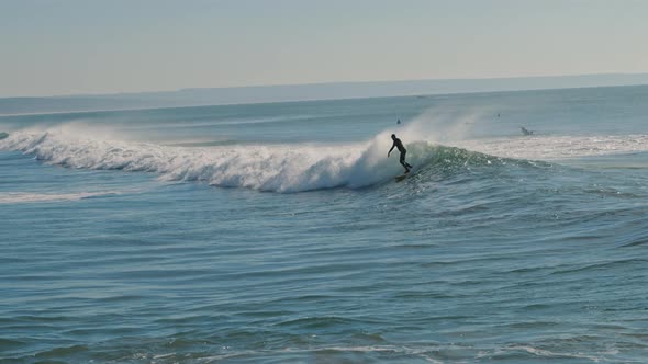 Surfer riding a big blue wave of the Atlantic Ocean on a beautiful sunny day alt