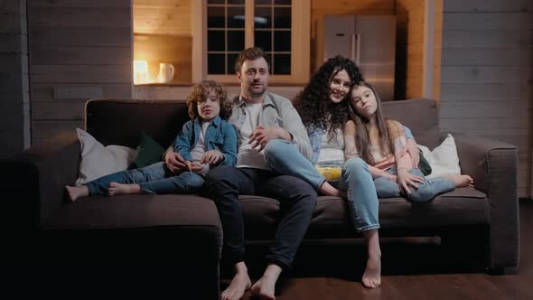 Family Watching a Movie Together at Home Eating Popcorn and Hugging alt
