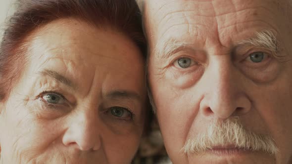 elderly couple looking at the camera with serious look, closeup