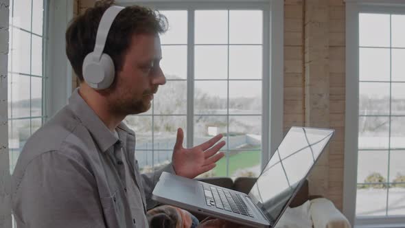 Man with Headphones Working on Video Call While His Children are Having Fun alt