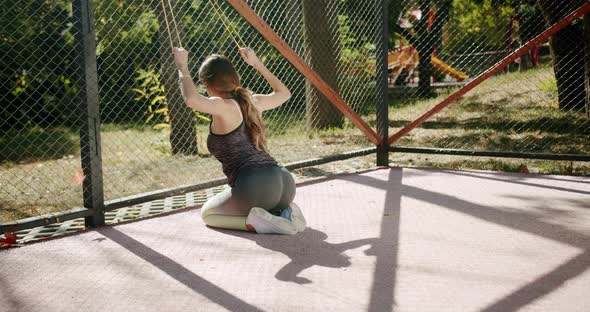 A Young Female Athlete Does Exercise Lunges with an Elastic Band alt